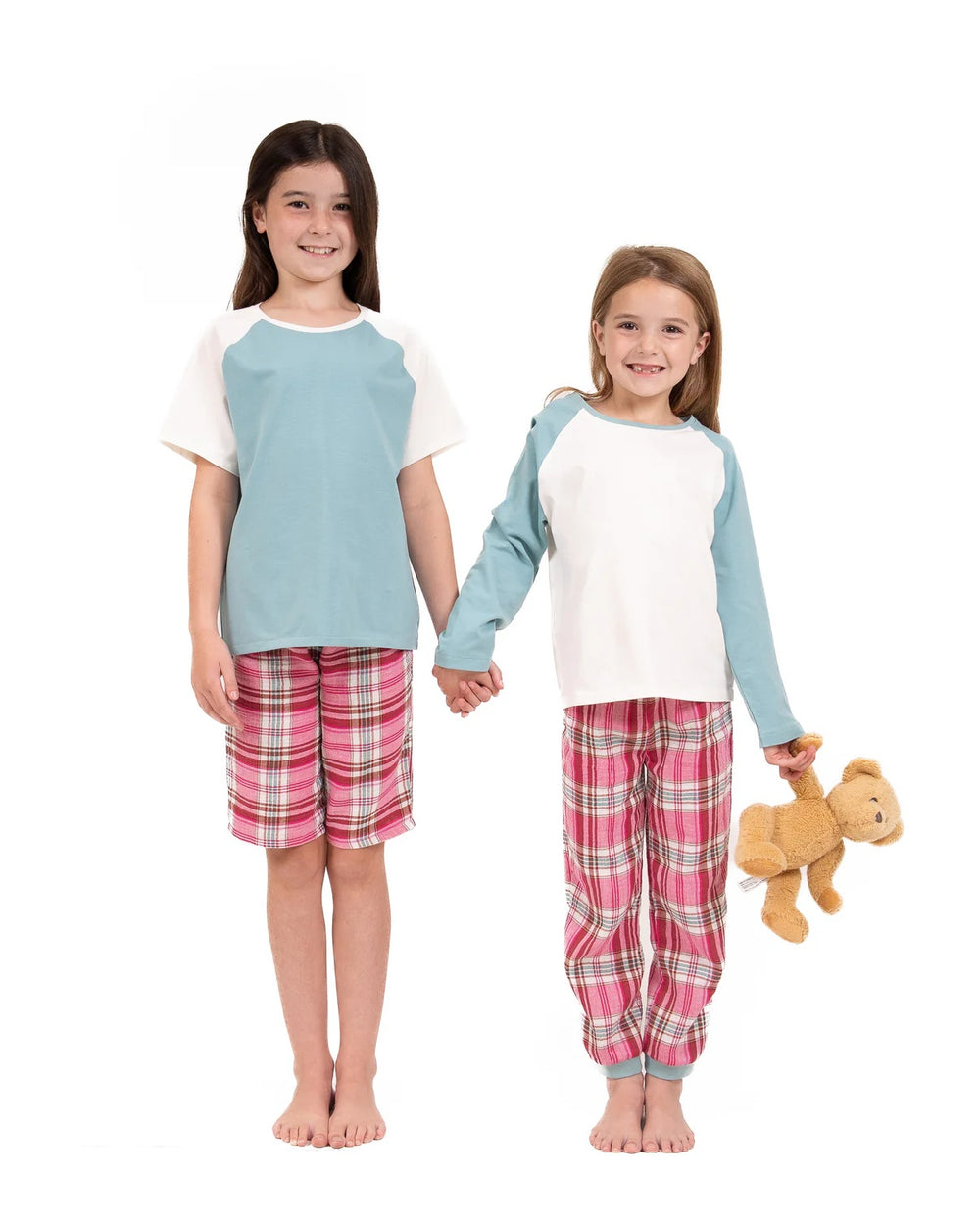 Children wearing the Child/Teen Cadal Pyjamas sewing pattern from Little Rosy Cheeks on The Fold Line. A pyjamas pattern made in jersey fabric (top) and jersey, woven cotton, or double gauze fabric (bottoms), featuring a top with short or long raglan sleeves and short or long bottoms with an elastic waist.