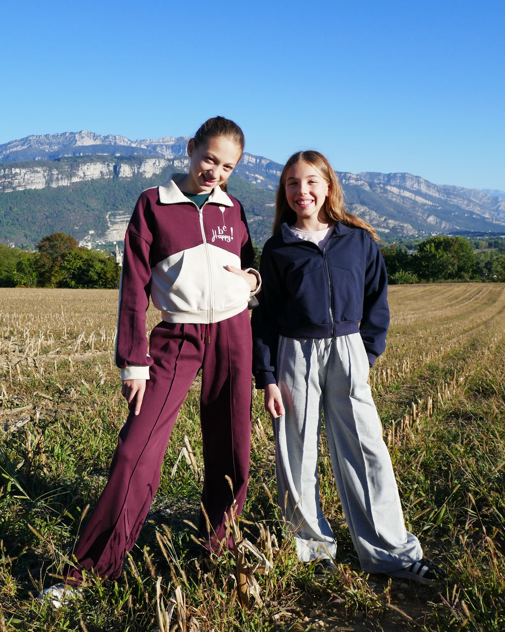 Girls wearing the Child/Teen Kald Zipped Sweatshirt sewing pattern from Petits D'om on The Fold Line. A zipped sweatshirt pattern made in fleece or french terry fabric, featuring a collar, dropped shoulders, pockets, and a slightly cropped length.