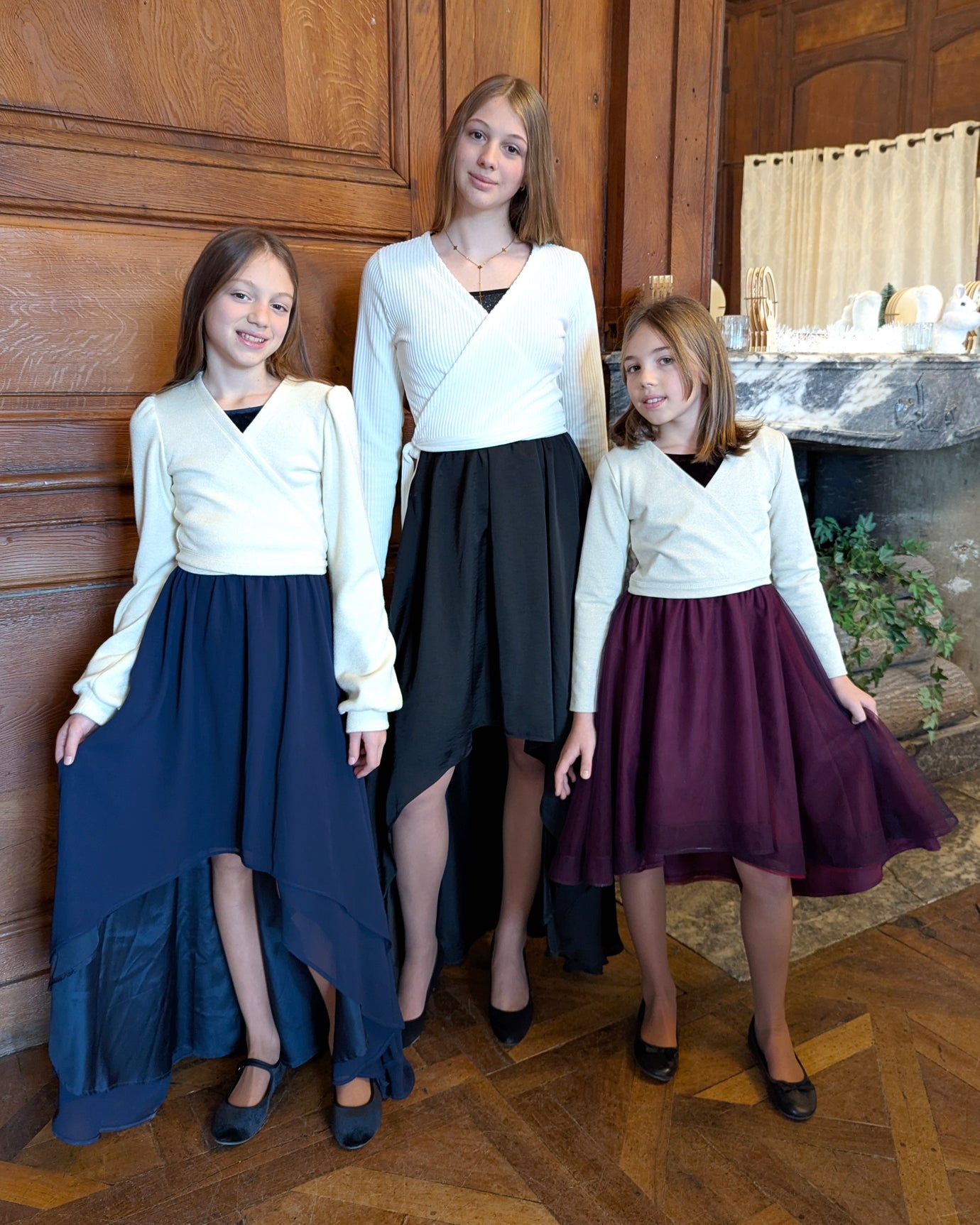 Girls wearing the Child/Teen Mazurka Wrap Sweater or Cardigan sewing pattern from Petits D'om on The Fold Line. A sweater or cardigan pattern made in knit fabric, featuring a cross over front and long fitted or bishop sleeves.