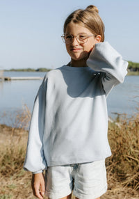Girl wearing the Child/Teen Miss Granite Sweatshirt sewing pattern from Maison Fauve on The Fold Line. A sweatshirt pattern made in knit fabric, featuring a loose fit, round neckline, elongated shoulder line, and voluminous long sleeves.