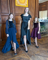 Girls wearing the Child/Teen Reverence Dress sewing pattern from Petits D'om on The Fold Line. A dress pattern made in knit fabric and muslin, georgette crepe, satin crepe, viscose, or tulle fabric, featuring a round or square neckline, sleeveless bodice, butterfly sleeves, or bishop sleeves, and high-low hemline.