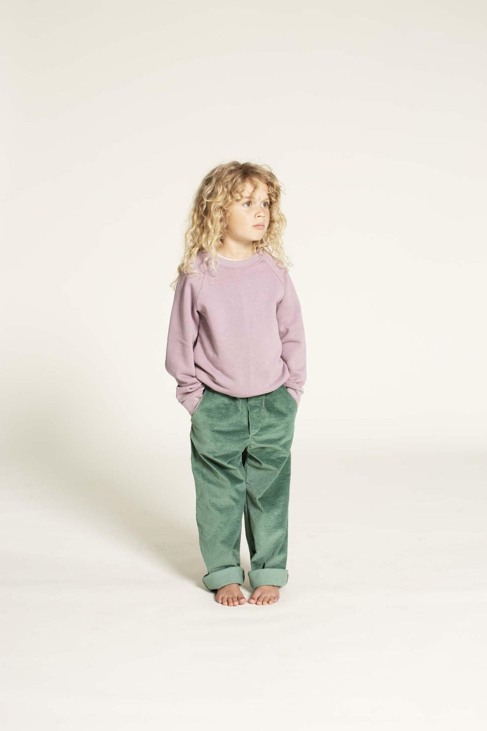 Child wearing the Children’s Woven Pants sewing pattern from Wardrobe by Me on The Fold Line. A pants pattern made in linen, cotton, light canvas, corduroy, or denim fabric, featuring an elastic waist, mock fly, straight leg, and side and back pockets.