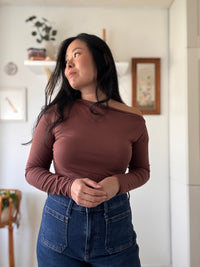 Woman wearing the Cinnamon Long Sleeve Top sewing pattern from Sew Bake Make on The Fold Line. A top pattern made in knit fabric, featuring a close fit, one-shoulder cut, and long sleeves.
