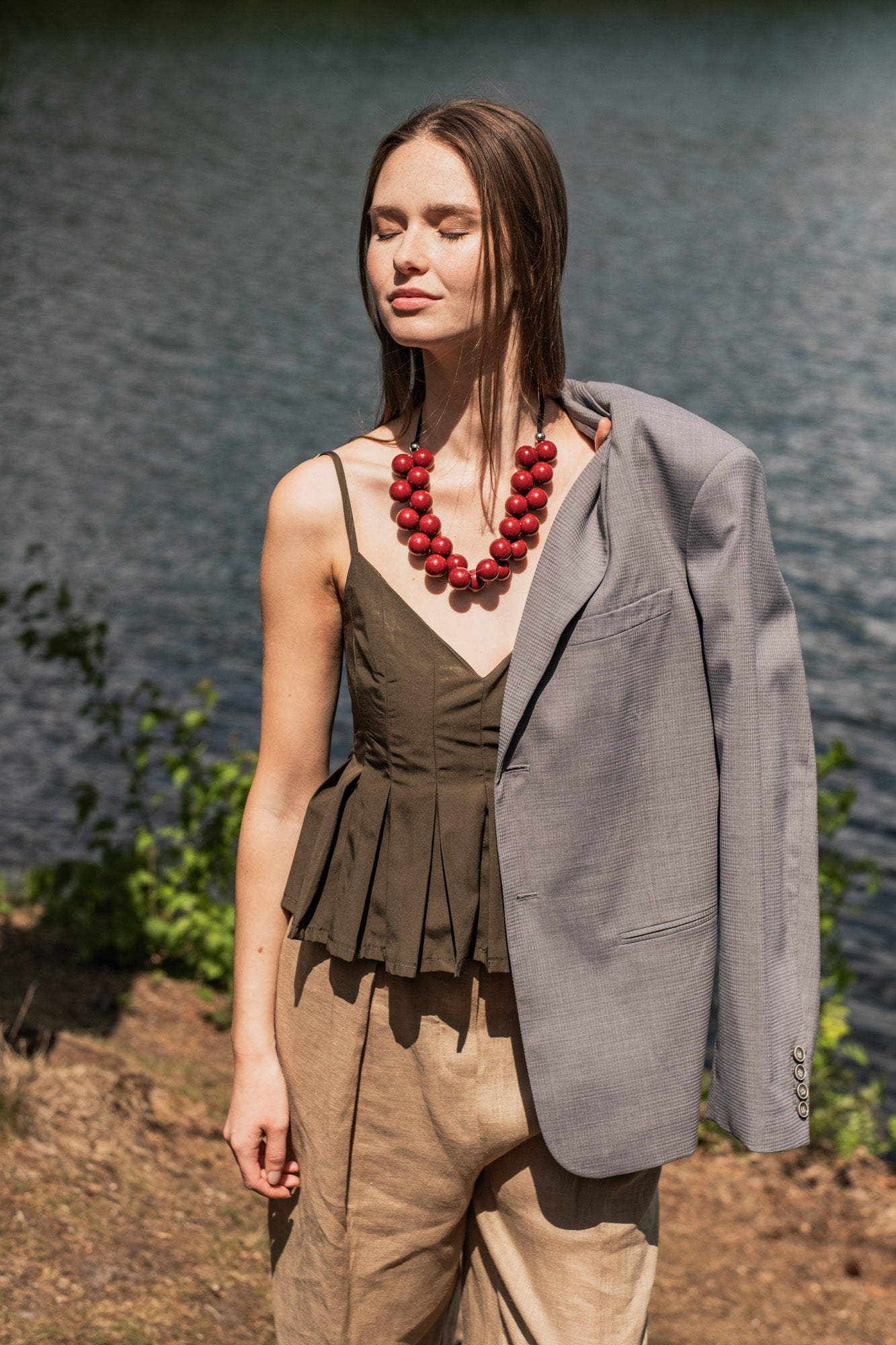 Woman wearing the Clementine Top sewing pattern from Fibre Mood on The Fold Line. A top pattern made in poplin, cotton twill, nylon, viscose crepe, viscose satin, or lyocell fabric, featuring thin straps, a deep V-neckline, and pleats that fan out towards the waist for a peplum effect.