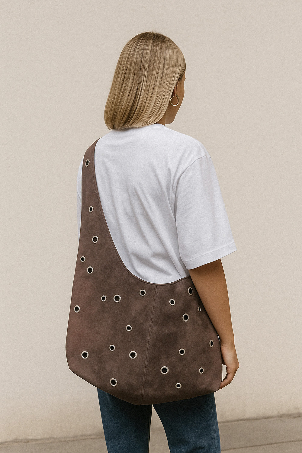 Woman wearing the Cleo Hobo Bag sewing pattern from JULIANA MARTEJEVS on The Fold Line. A crossbody bag pattern made in faux leather fabric, featuring decorative eyelets.