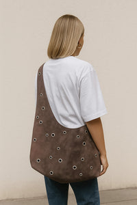 Woman wearing the Cleo Hobo Bag sewing pattern from JULIANA MARTEJEVS on The Fold Line. A crossbody bag pattern made in faux leather fabric, featuring decorative eyelets.