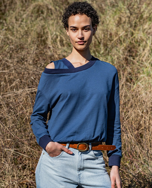 Woman wearing the Coco Sweatshirt sewing pattern from Fibre Mood on The Fold Line. A top pattern made in knit fabric, featuring a relaxed fit, long sleeves, and cut-out shoulder detail.
