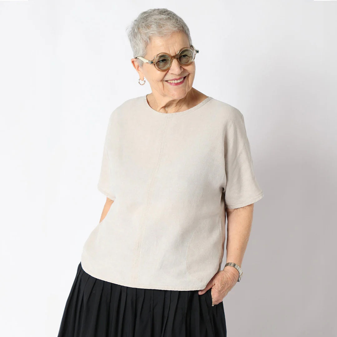 Woman wearing the Cora Top sewing pattern from Tessuti Fabrics on The Fold Line. A top pattern made in linen, linen blends, silk, viscose, or wool crepe fabric, featuring a round neckline, mid-length sleeves, curved hem, in-seam pockets, and hip length.