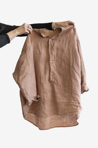 Person holding the Cornell Shirt sewing pattern from Elbe Textiles on The Fold Line. A shirt pattern made in cotton shirting, washed linen, lyocell, silk noil, hemp, cotton cheesecloth, or cotton voile fabric, featuring an oversized fit, drop shoulders, grandpa collar, button up placket, and long sleeves.