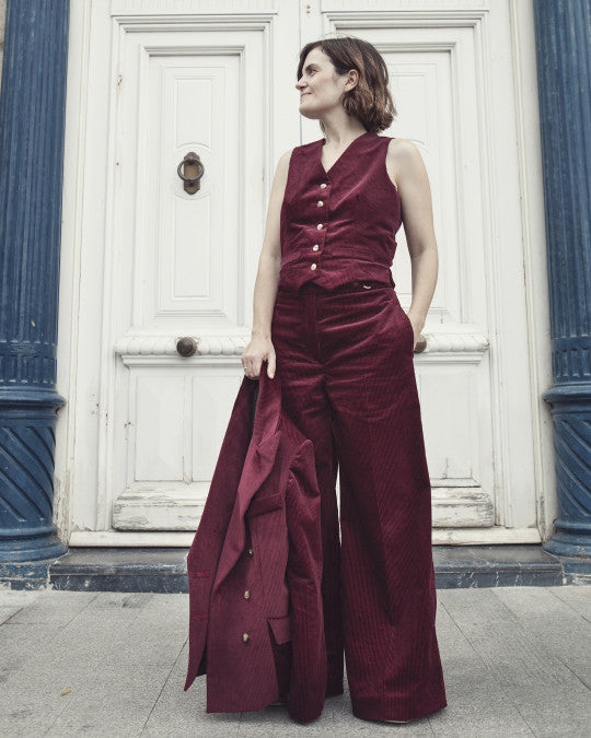 Woman wearing the Costera Waistcoat sewing pattern from Pauline Alice on The Fold Line. A waistcoat pattern made in cotton twill, corduroy, wool crepe, woollen, or linen fabric, featuring a fitted silhouette with front and back waist darts, V-neckline, front button closure, faux welt pockets, and side slits. 