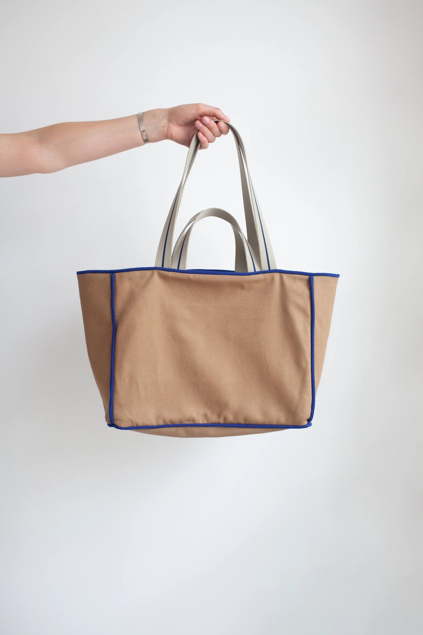The Day Tote sewing pattern from the Modern Sewing Co. on The Fold Line. A bag pattern made in cotton canvas or waxed cotton fabric, featuring a roomy interior, flat base, pockets, decorative piping, and dual handles.