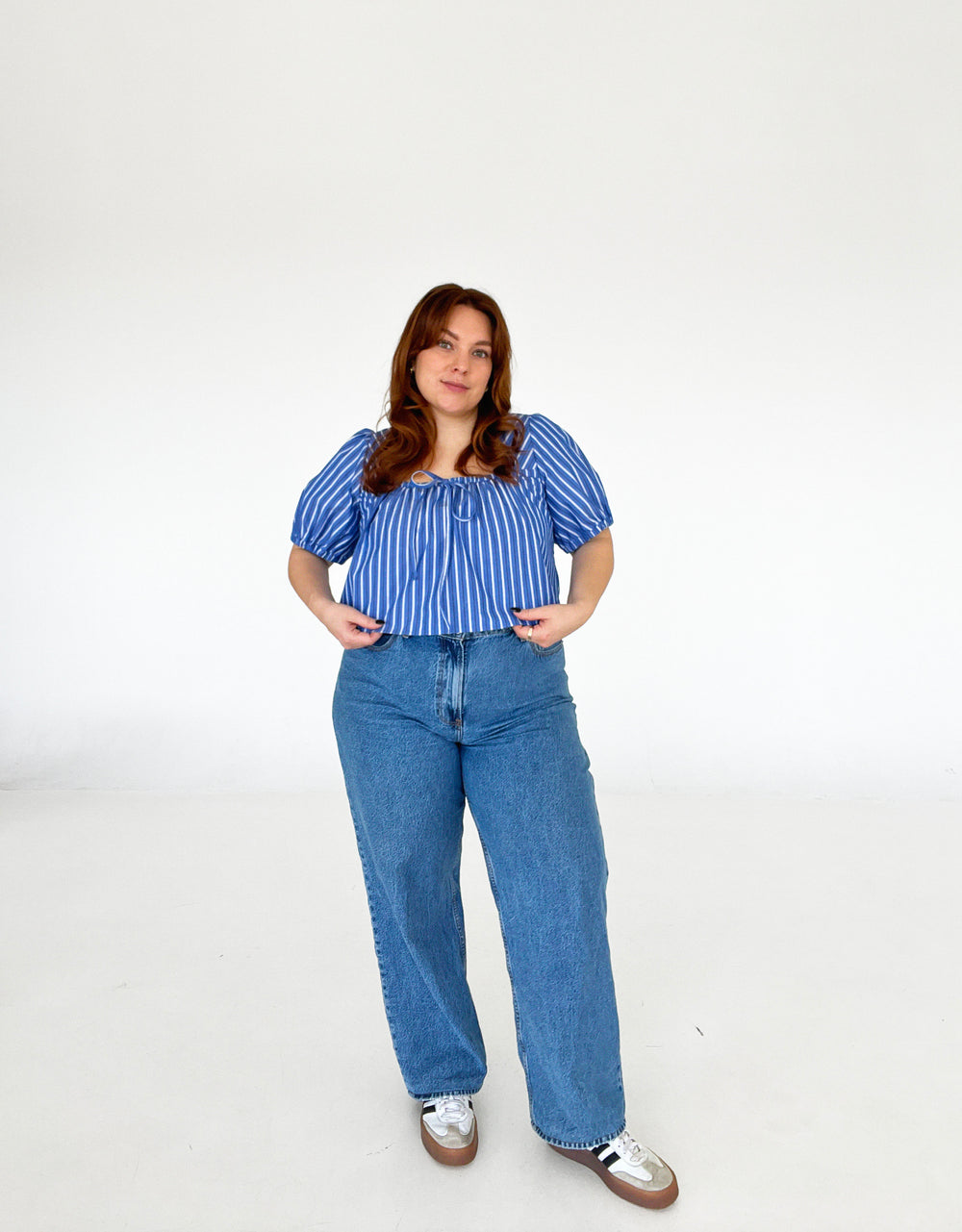 Woman wearing the Dayscape Top sewing pattern from Les Perlines on The Fold Line. A blouse pattern made in cotton, linen, rayon, viscose, or tencel twill fabric, featuring a square neckline with ties, mid-length puff sleeves, and cropped length.