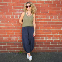 Woman wearing the Demi Pants sewing pattern from Tessuti Fabrics on The Fold Line. A pants pattern made in linen, lightweight wool, cotton, viscose, silk faille or crepe fabric, featuring an elasticised waist, full legs, stitched-down side pockets, and a pleat detail at the front and back hemline.