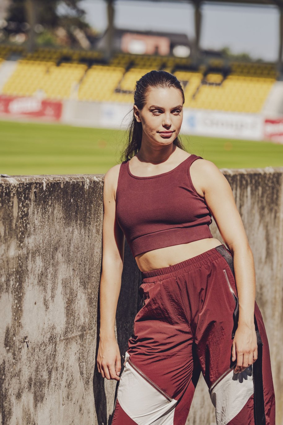 Woman wearing the Denver Top sewing pattern from Fibre Mood on The Fold Line. A sports top pattern made in stretch jersey, power stretch, rib knit, microfibre, or supplex-like fabric, featuring a close fit, cropped length, and elastic in the hem for support.