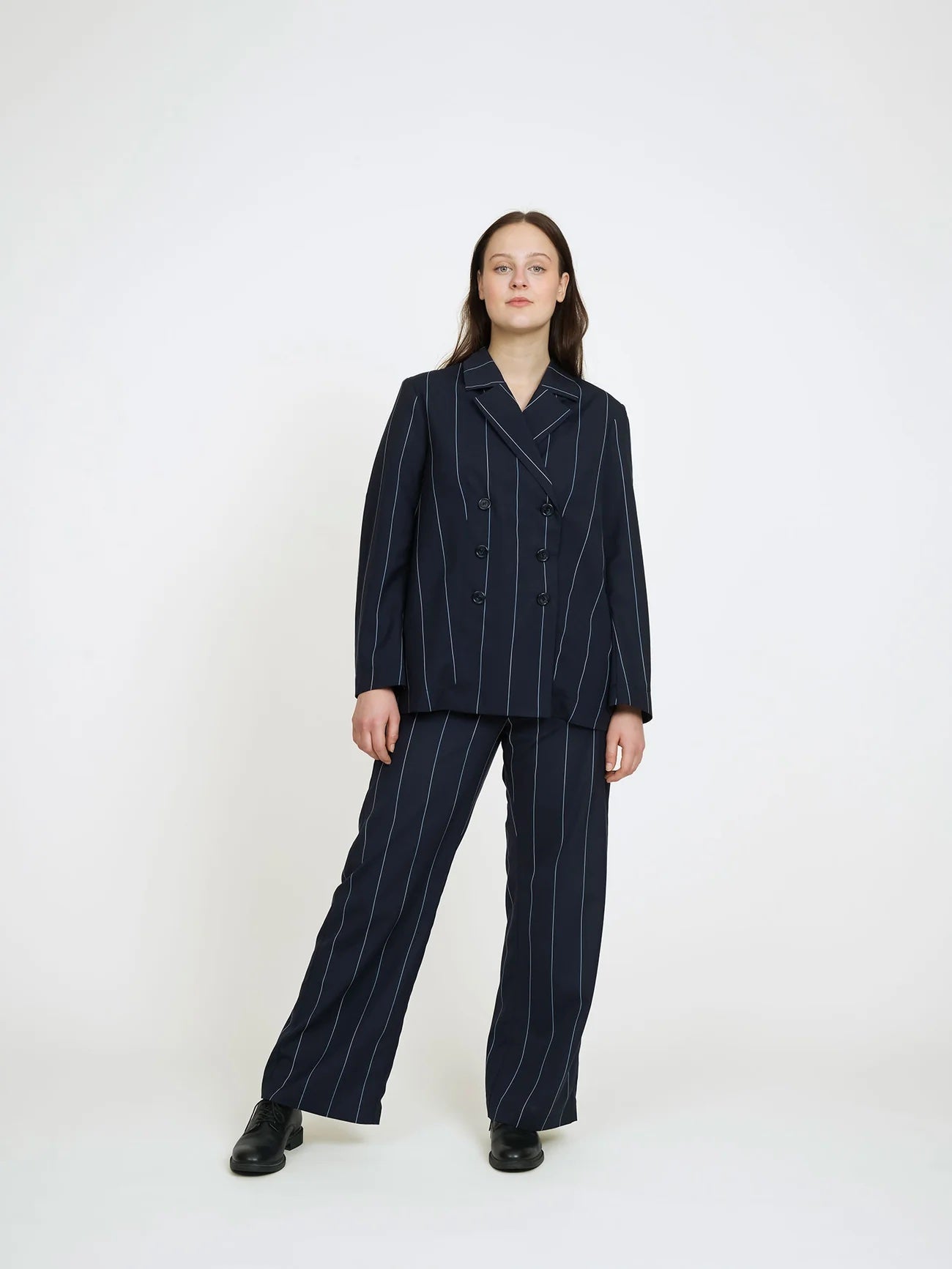 Woman wearing the Double-Breasted Jacket sewing pattern from The Assembly Line on The Fold Line. An unlined blazer pattern made in light to medium weight fabric, featuring a double-breasted front with buttons, darts, and two-piece sleeves.