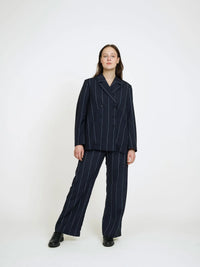 Woman wearing the Double-Breasted Jacket sewing pattern from The Assembly Line on The Fold Line. An unlined blazer pattern made in light to medium weight fabric, featuring a double-breasted front with buttons, darts, and two-piece sleeves.