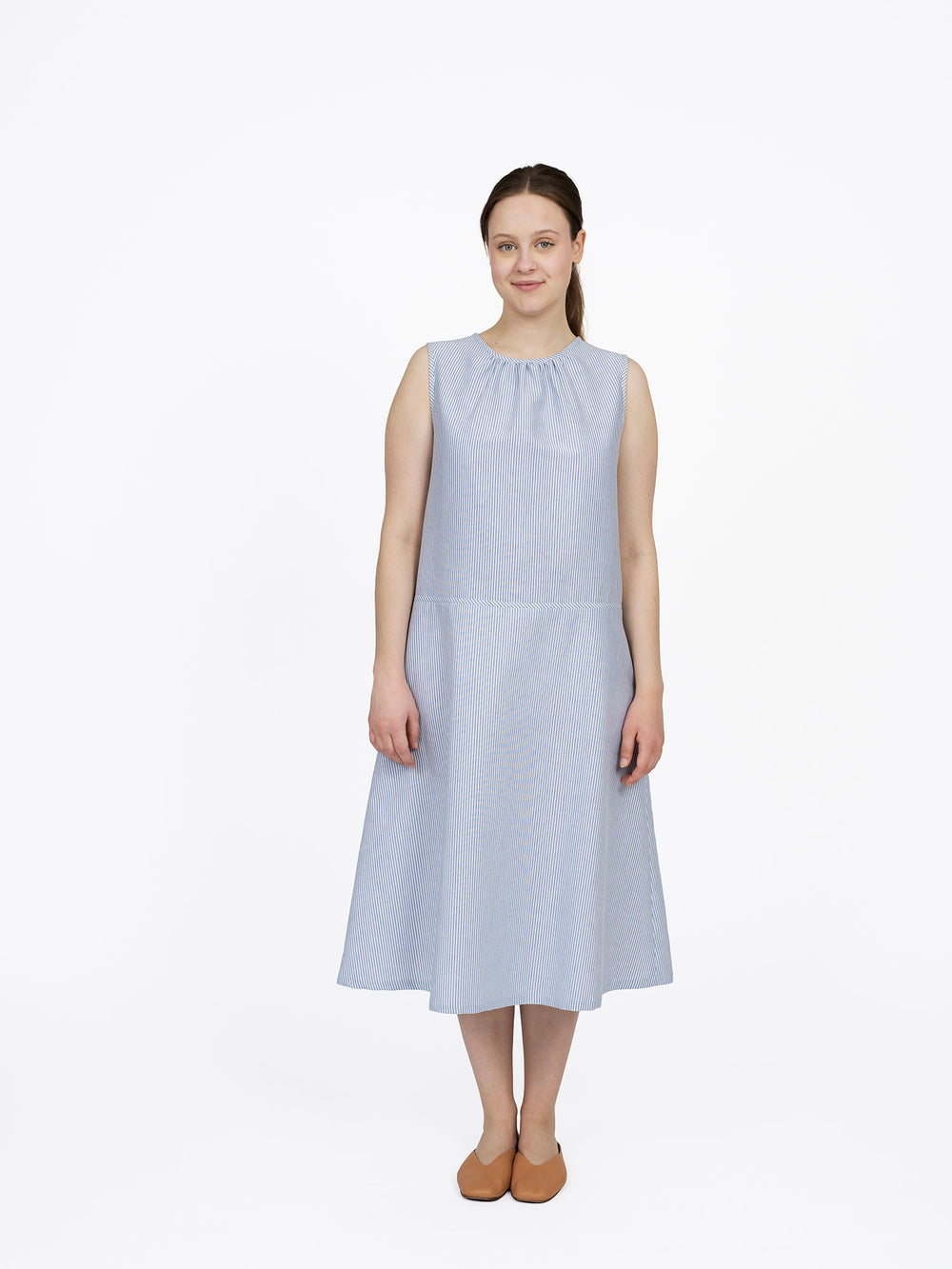 Woman wearing the Drop-waist Dress sewing pattern from The Assembly Line on The Fold Line. A sleeveless dress pattern made in light to medium weight fabric, featuring a round neckline with gathers, dropped waist, and midi length.