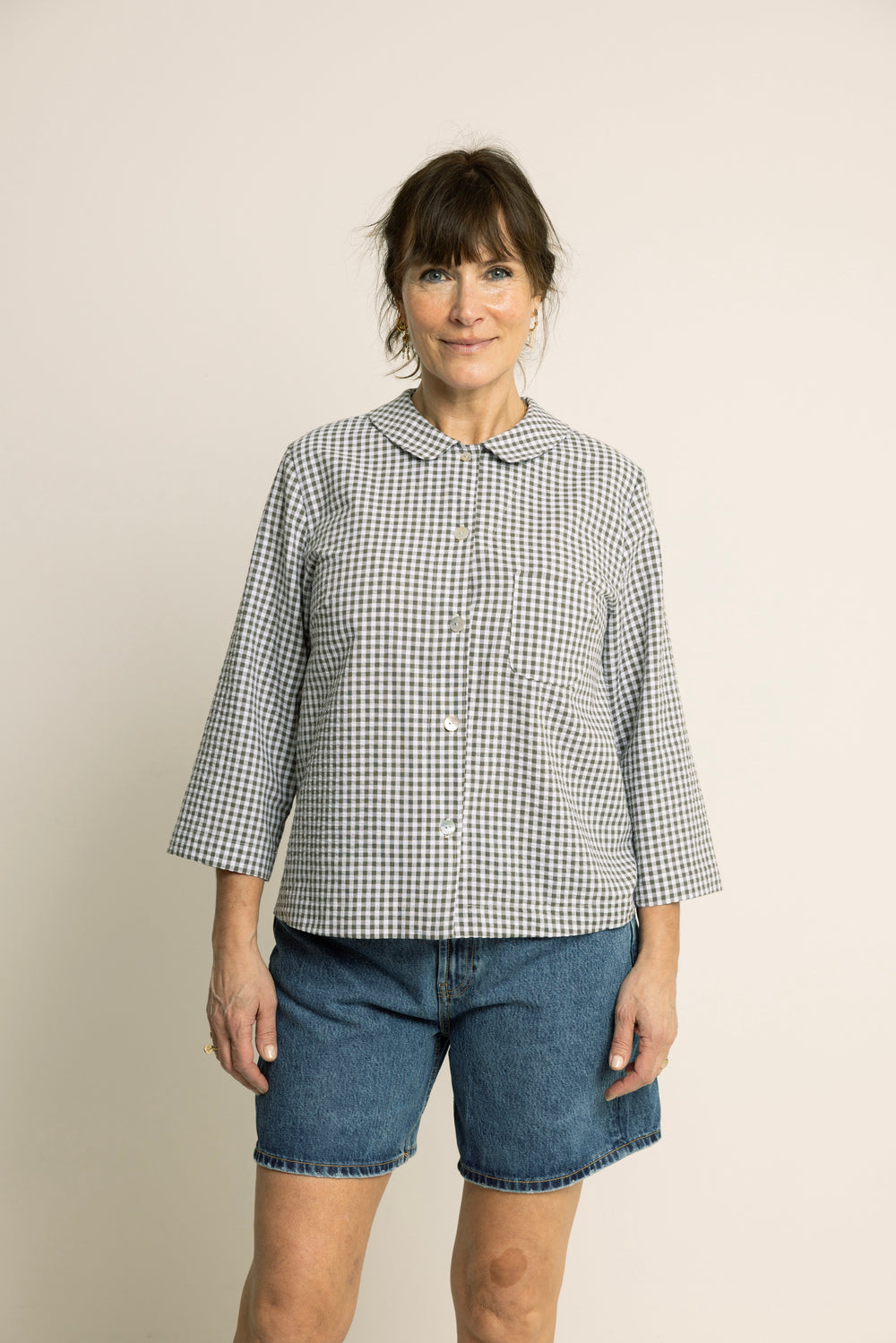 Woman wearing the Dukke Blouse sewing pattern from Wardrobe by Me on The Fold Line. A shirt pattern made in cotton or linen fabric, featuring a Peter Pan collar, button front, chest pocket, and 3/4 length sleeves.