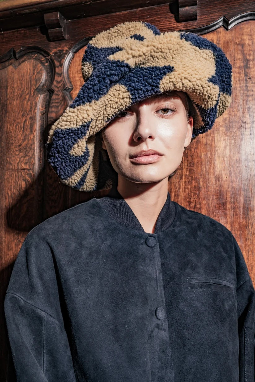 Woman wearing the Eddie Hat sewing pattern from Fibre Mood on The Fold Line. A bucket hat pattern made in quilted fabric or teddy fabric, featuring an extra-wide brim that can be shaped with a metal wire in the brim.
