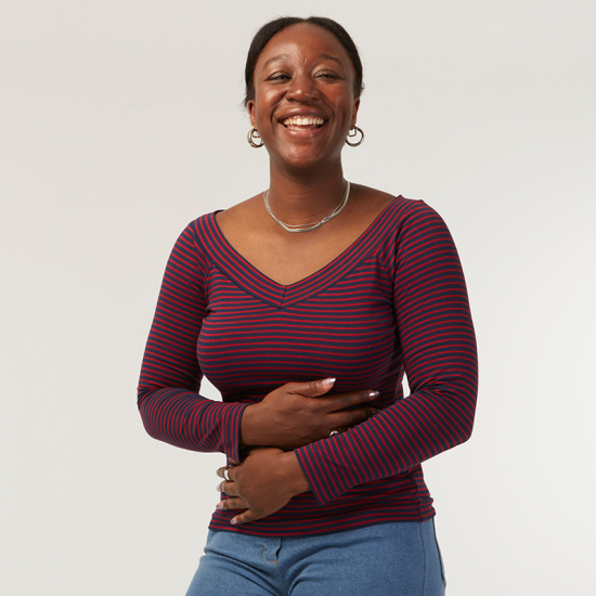 Woman wearing the Ehola T-shirt sewing pattern from Coralie Bijasson on The Fold Line. A fitted T-shirt pattern made in knit fabric, featuring a V-shaped ballet neckline and long sleeves.