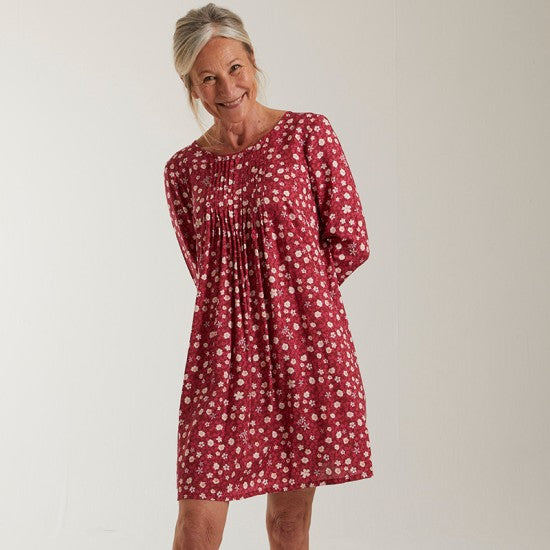 Woman wearing the Eileen Dress sewing pattern from Coralie Bijasson on The Fold Line. A dress pattern made in viscose crepe, silk satin, or cotton fabric, featuring a round neckline, pleated bodice, long sleeves, side pockets, and mini length.