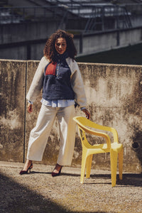 Woman wearing the Elan Sweater sewing pattern from Fibre Mood on The Fold Line. A sweater pattern made in teddy fabric, sherpa fleece, (faux) fur, bouclé, felt, leather, chunky knit fabric, or sweater fabric, featuring a relaxed fit, stand-up collar, snap placket, long raglan sleeves, and zip pockets.