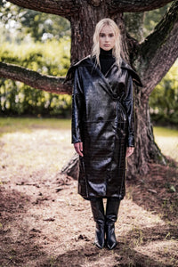 Woman wearing the Elda Coat sewing pattern from Fibre Mood on The Fold Line. A coat pattern made in wool or wool blend, gabardine, jacquard, leather, or technical coat fabric, featuring an oversized collar, diagonal seamlines, wrap front, pockets, and below knee length.