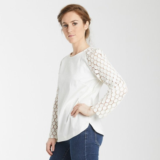 Woman wearing the Éléonore Top sewing pattern from Coralie Bijasson on The Fold Line. A blouse pattern made in quilting cotton, viscose, lace, or jersey fabric, featuring a round neckline, long raglan sleeves, and a rounded hemline.