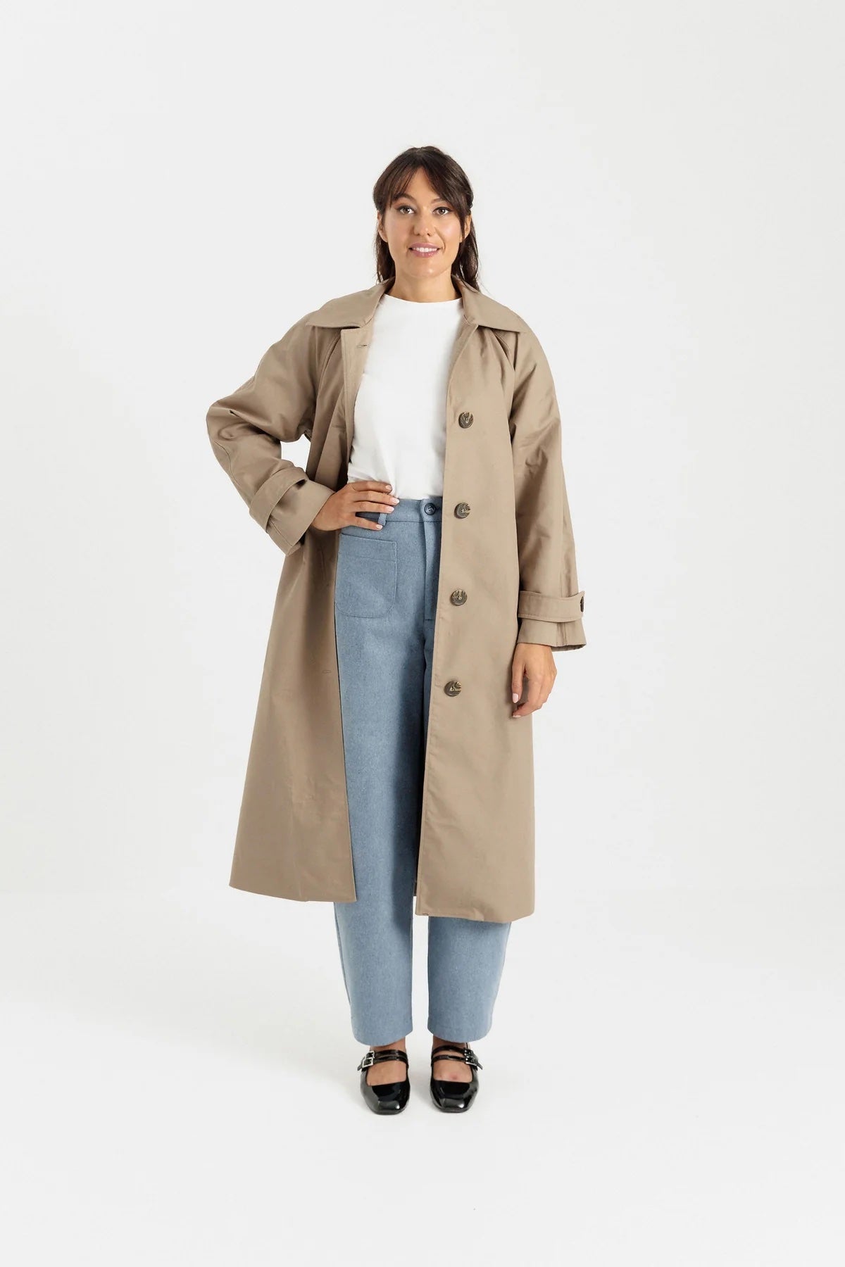 Woman wearing the Eliza Trench Coat sewing pattern from Papercut Patterns on The Fold Line. A trench pattern made in cotton drill, canvas, wool coating, denim, corduroy, or linen fabric, featuring a full lining, pointed collar, welt pockets and sleeve tabs.