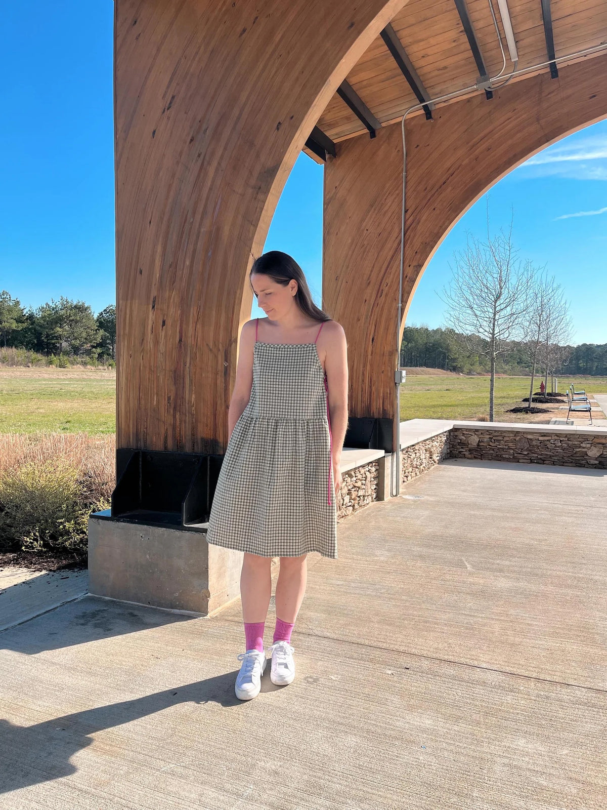 Woman wearing the Elma Dress sewing pattern from Me & Kiddo Patterns on The Fold Line. A dress pattern made in cotton or linen fabric, featuring adjustable straps, gathered skirt, side pockets, and knee length.