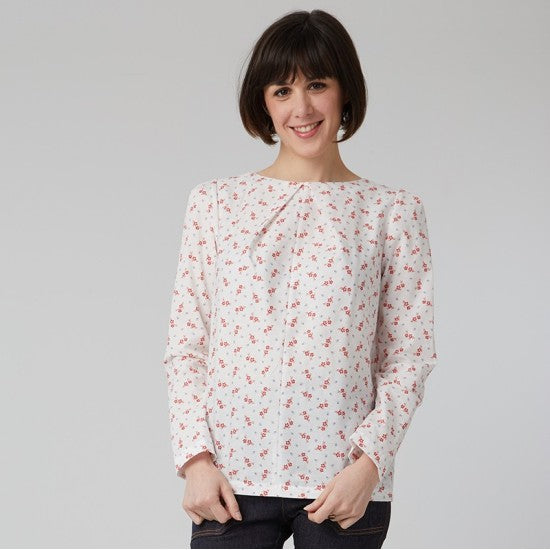 Woman wearing the Elvira Top sewing pattern from Coralie Bijasson on The Fold Line. A blouse pattern made in cotton, viscose, or silk fabric, featuring a round neckline, front neckline pleat, and long sleeves with pleats at the top.