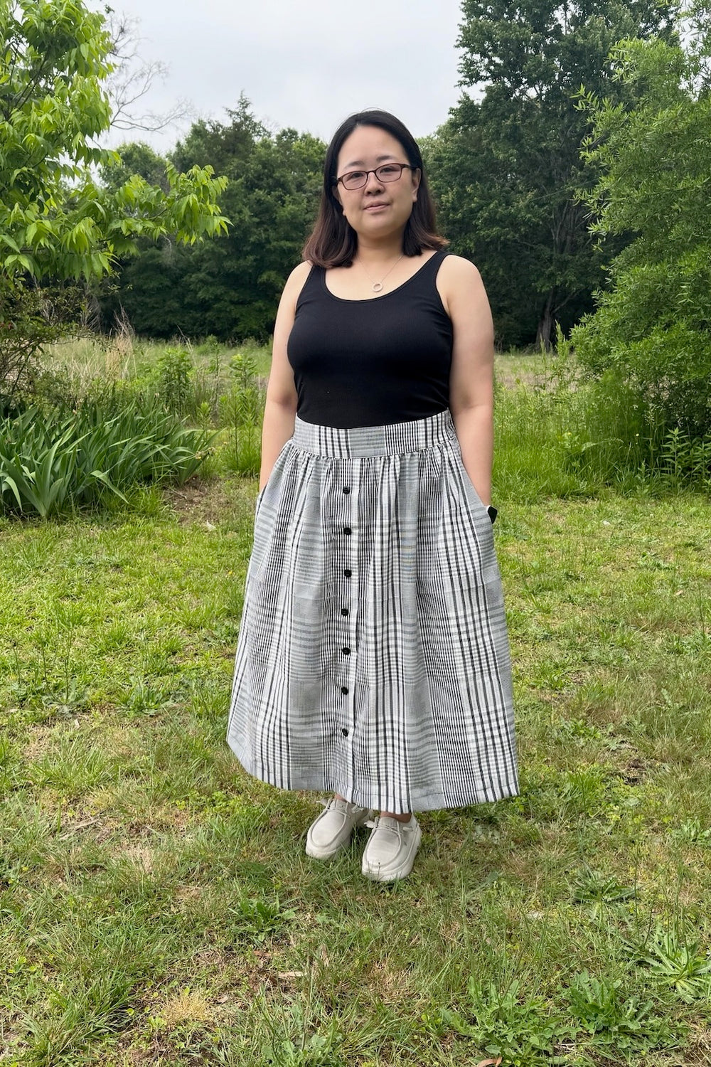 Woman wearing the Eucalyptus Skirt sewing pattern from Waves & Wild on The Fold Line. A skirt pattern made in cotton poplin or linen fabric, featuring a button front, flat front waistband, elasticated back waistband, gathers, pockets, and maxi length.
