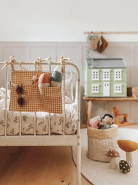 The Eva Bed Pocket sewing pattern from Me & Kiddo Patterns on The Fold Line. An organizer pattern made in cotton, cotton canvas, or linen fabric, featuring two pockets and narrow ties to attach to a bed or crib.