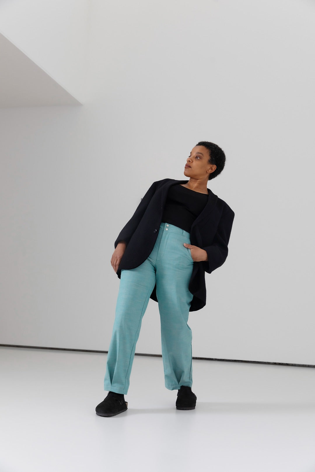 Woman wearing the Fairway Trousers sewing pattern from TAUKO on The Fold Line. A trousers pattern made in cotton, hemp, twill, or wool fabric, featuring a mid rise, fly front, belt loops, side pockets, and pleated hem.