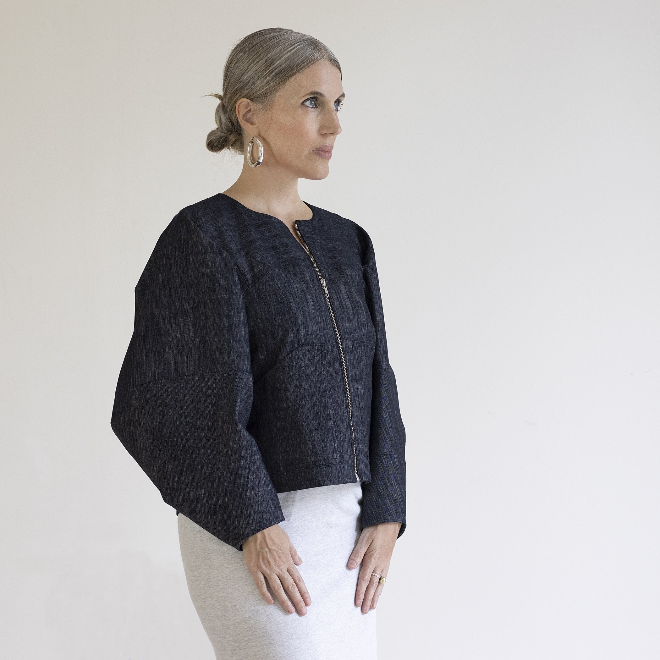 Woman wearing the Falda Jacket sewing pattern from Pattern Fantastique on The Fold Line. A jacket pattern made in denim or wool fabric, featuring a round neckline, zip front, pockets, and voluminous sleeves.