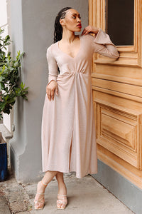 Woman wearing the Fiona Dress sewing pattern from JULIANA MARTEJEVS on The Fold Line. A dress pattern made in knit fabric, featuring a deep V-neckline, long flared sleeves, gathered front, front slit, and midi length.