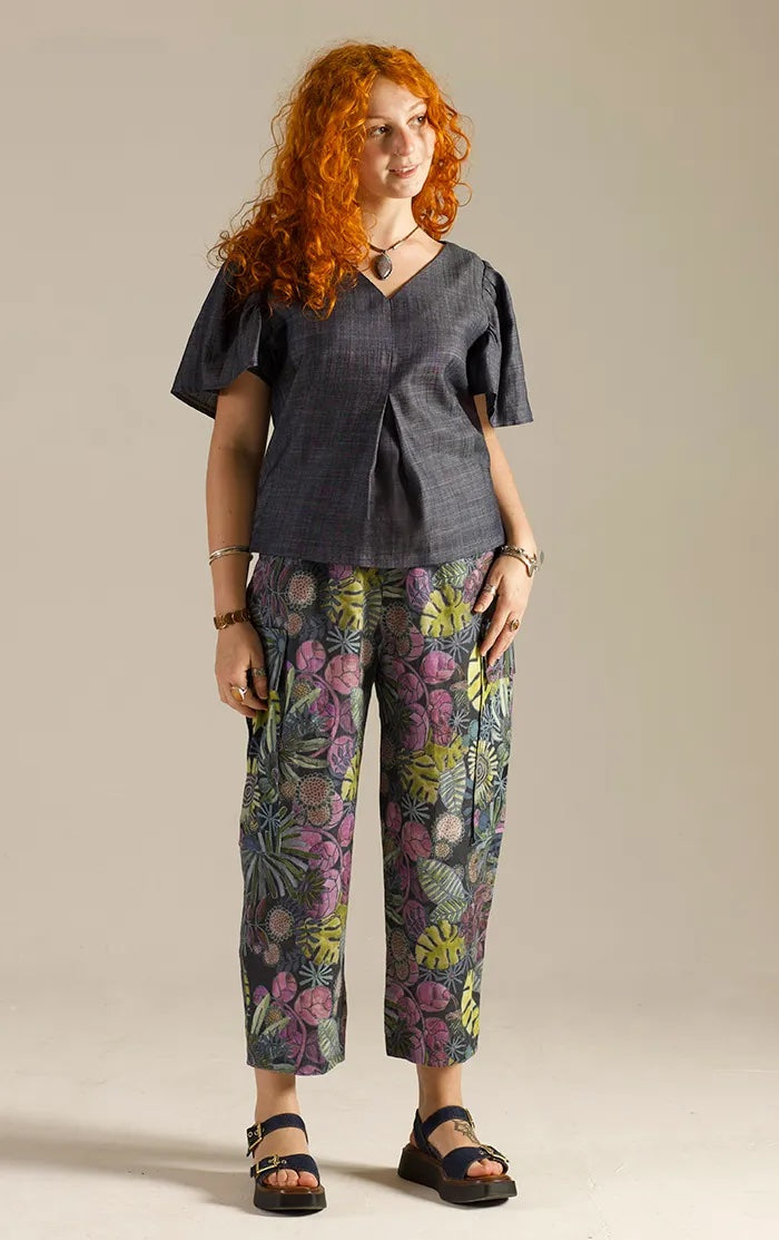 Woman wearing the Frill Sleeve Top sewing pattern from Sew Different on The Fold Line. A top pattern made in cotton lawn, cotton poplin, linen, silk, viscose, crepe, or corduroy fabric, featuring a V-neckline, inverted pleat below the bust, and gathered short sleeves.