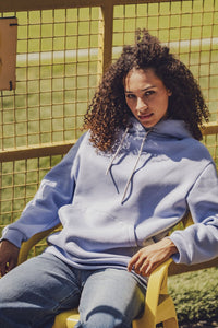 Woman wearing the Fritzi Hoodie sewing pattern from Fibre Mood on The Fold Line. A hoodie pattern made in sweater fabric, French terry, punto di Roma, scuba, lightweight neoprene, or teddy fabric, featuring a relaxed fit, long sleeves, kangaroo pocket, and hood with a drawstring.