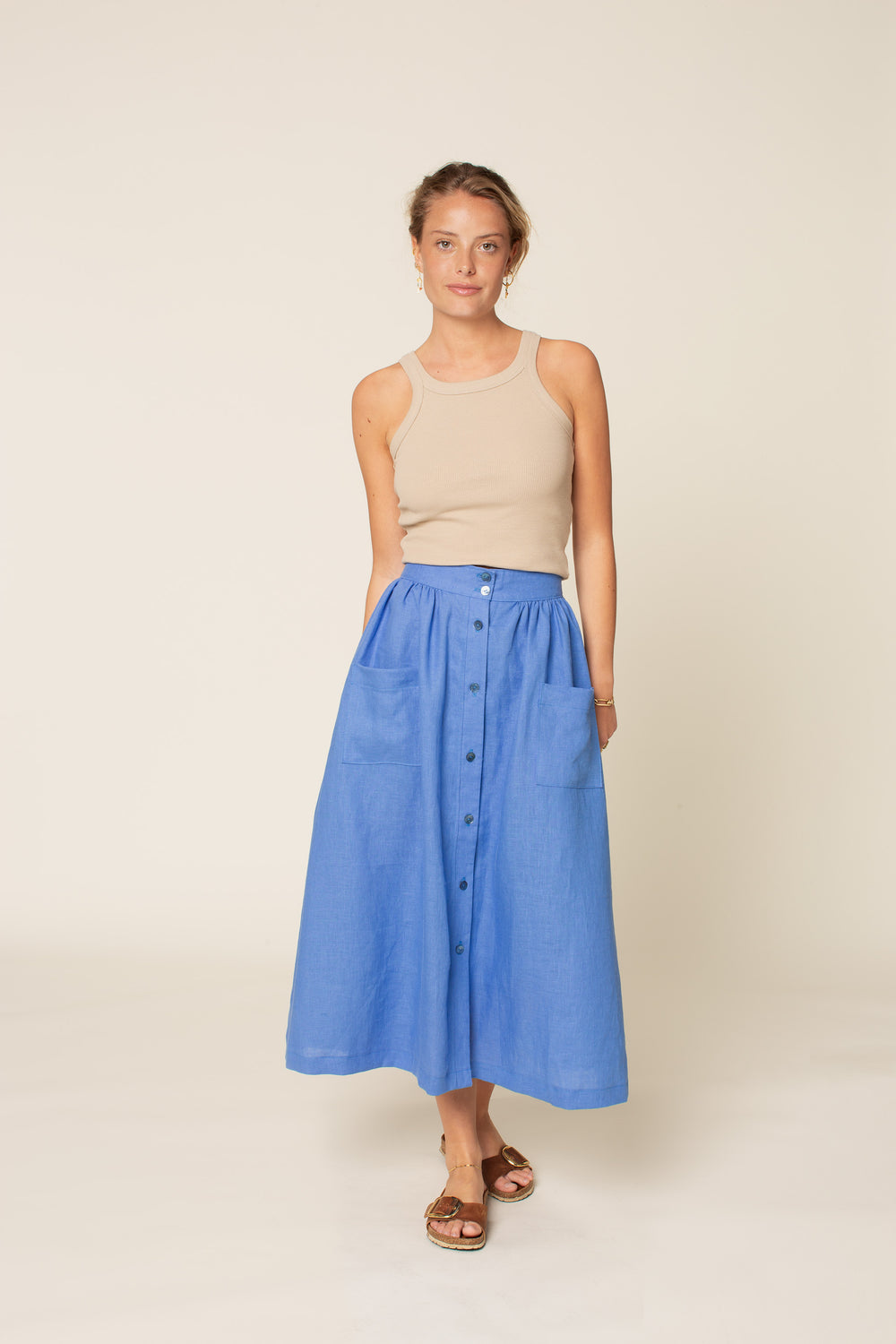 Woman wearing the Front Button Skirt sewing pattern from Wardrobe by Me on The Fold Line. A skirt pattern made in cotton, viscose, linen, or double gauze fabric, featuring a wide waistband, gathers, front button placket, patch pockets, and midi length.