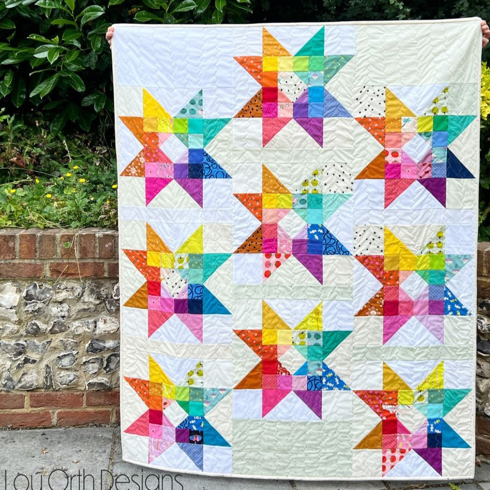 The Gemburst Quilt sewing pattern from Lou Orth Designs on The Fold Line. A quilt pattern made in quilting cotton fabric, featuring colourful stars in a scrap friendly repeat block design.