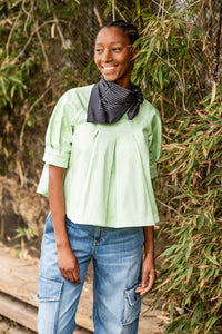 Woman wearing the Georgie Top sewing pattern from Fibre Mood on The Fold Line. A blouse pattern made in lyocell, poplin, or woven jacquard fabric, featuring an A-line silhouette, front and back pleats, and short raglan balloon sleeves with cuffs.