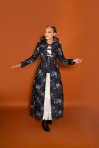Woman wearing the Germaine Corset Coat sewing pattern from Madalynne on The Fold Line. A coat pattern made in denim, twill, or brocade fabric, featuring an oversized hood, front ties, corset-style panelling, and lace-up back.