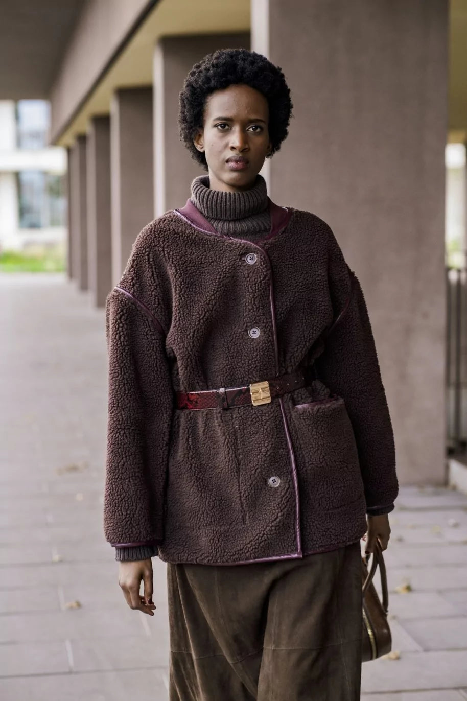 Woman wearing the Greta Jacket sewing pattern from Fibre Mood on The Fold Line. A jacket pattern made in teddy, faux shearling, bouclé, or soft felt fabric, featuring an oversized fit, bound seams and edges, bound buttonholes, and welt pockets.