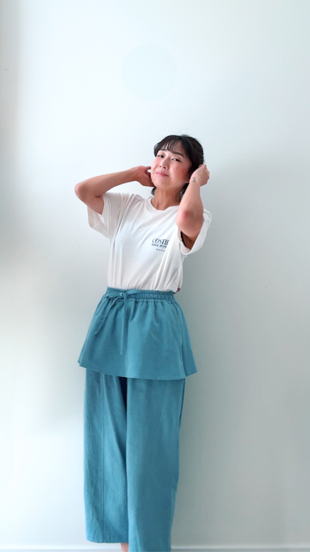 Woman wearing the Hanoi Pants sewing pattern from Sewing Therapy on The Fold Line. A pants pattern made in lightweight denim or chambray, cotton-tencel twill, poly suiting blend, mid-weight cotton twill, tencel (lyocell) twill, double gauze, linen-viscose, or linen-tencel blend fabric, featuring a skirt-over-pants silhouette, relaxed fit, elastic waistband, drawstring, pockets, and cropped length.