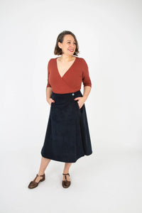 Woman wearing the Harriet Skirt sewing pattern from Sew Over It on The Fold Line. A wrap skirt pattern made in denim, chambray, corduroy, cotton canvas or twill, brocade, or wool fabric, featuring an A-line silhouette, button closure, and welt pockets in the forward side seams.