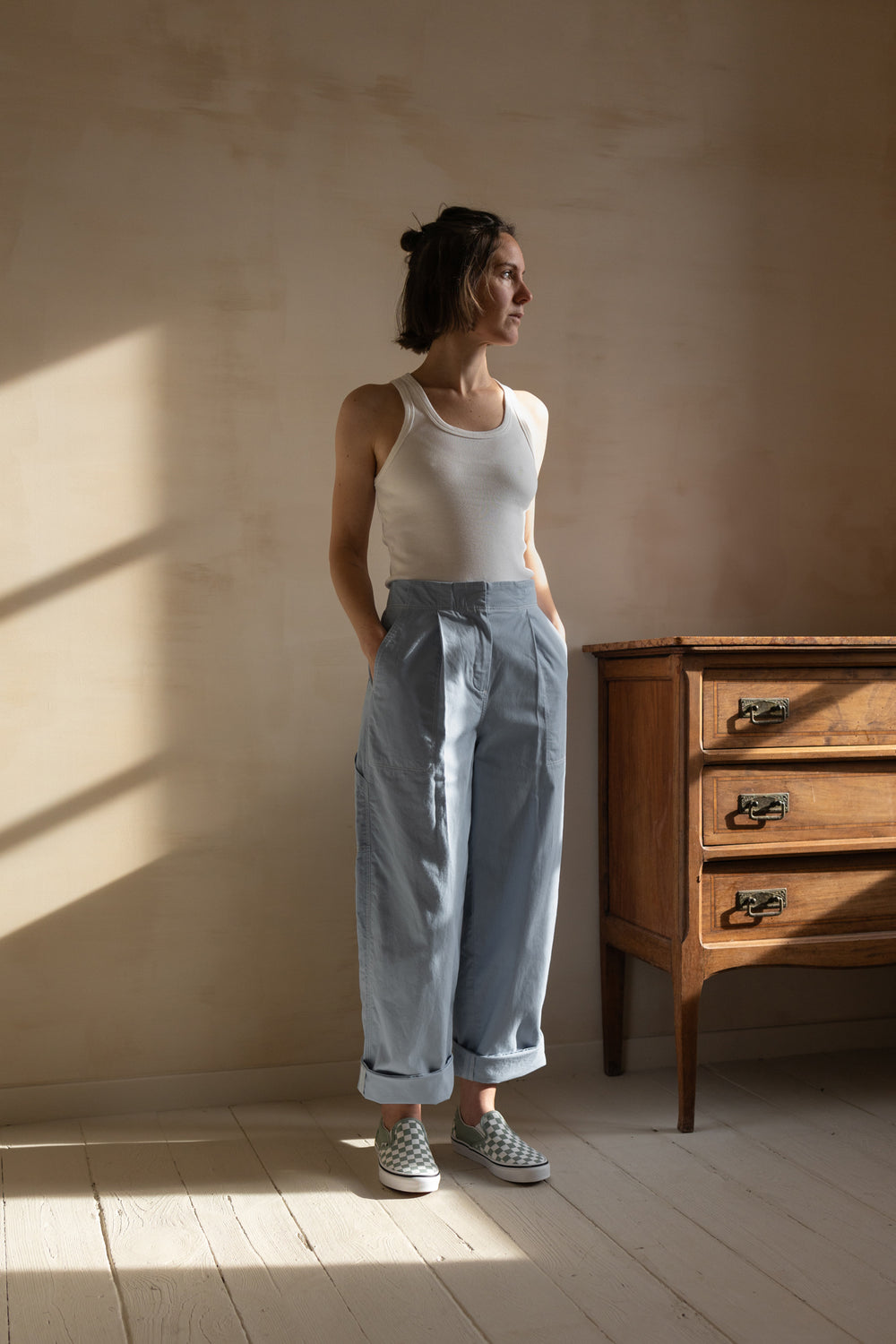 Woman wearing the Harry Utility Pants sewing pattern from Ready to Sew on The Fold Line. A pants pattern made in cotton gabardine, cotton twill, or lightweight denim fabric, featuring a high waist, front pleats, straight cut, pockets, adjustable back cinch, and topstitching.