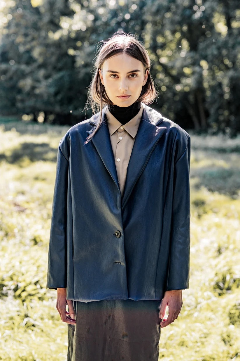 Woman wearing the Herman Blazer sewing pattern from Fibre Mood on The Fold Line. A blazer pattern made in wool, wool blend, gabardine, twill, sturdy suiting, jacquard, or leather fabric, featuring an oversized silhouette, straight cut, shoulder pads, front and back seams, pockets, and a button fastening.