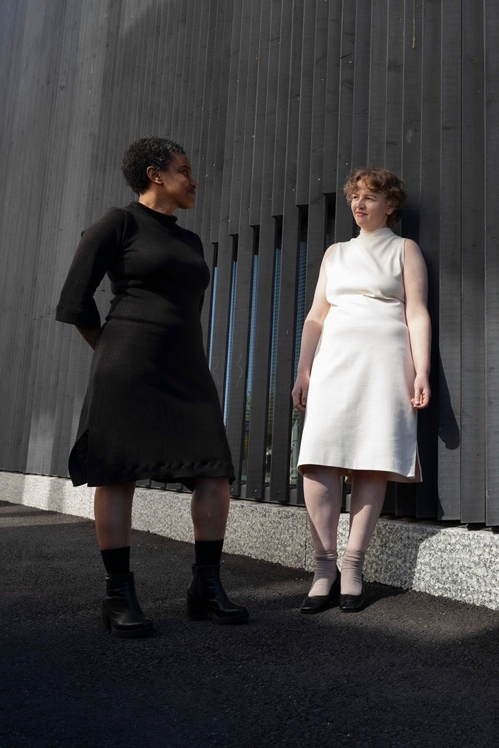 Women wearing the Hiutale Dress sewing pattern from TAUKO on The Fold Line. A sleeveless or 3/4 sleeve dress pattern made in knit fabric, featuring a high neckline, sleeve and hem slits, and knee length.