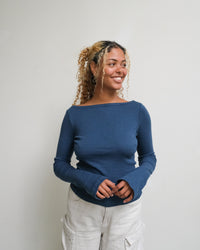 Woman wearing the Honeygirl Tee Expansion sewing pattern from Paradise Patterns on The Fold Line. A top pattern made in knit fabric, featuring a boat neck and long sleeves.