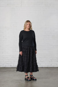 Woman wearing the Howerdel Skirt sewing pattern from Elbe Textiles on The Fold Line. A skirt pattern made in rayon, silk, washed linen, or soft cotton fabric, featuring a fitted waist, gathered tiers, and midi length.